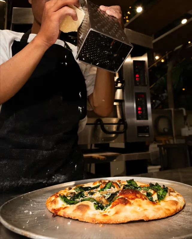 Chef grating cheese on pizza