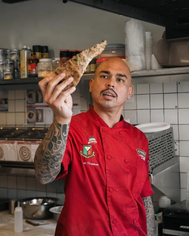 Chef holding pizza slice in kitchen