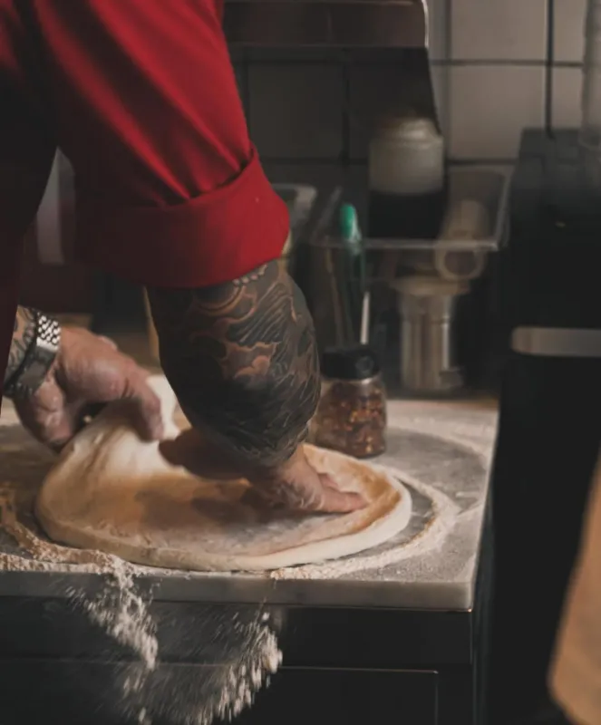 Chef spreading pizza dough in kitchen