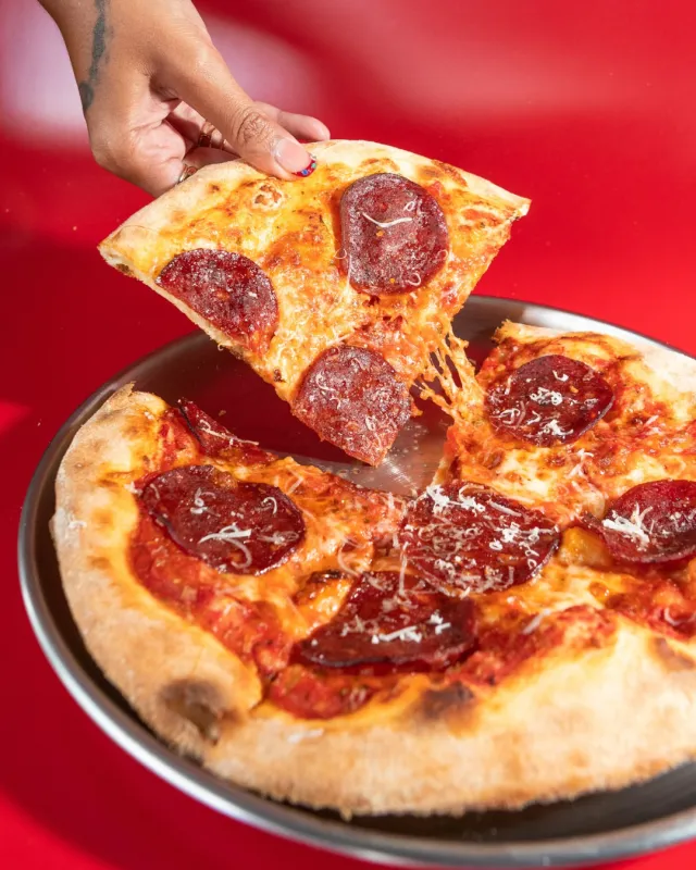 Pepperoni pizza slice on red background